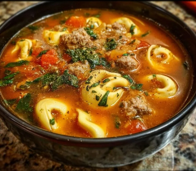 A delicious bowl of sausage tortellini soup garnished with parsley.