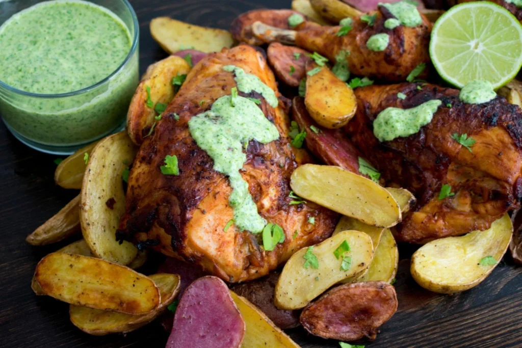 Plate of Peruvian chicken drizzled with creamy green sauce, garnished with fresh herbs.