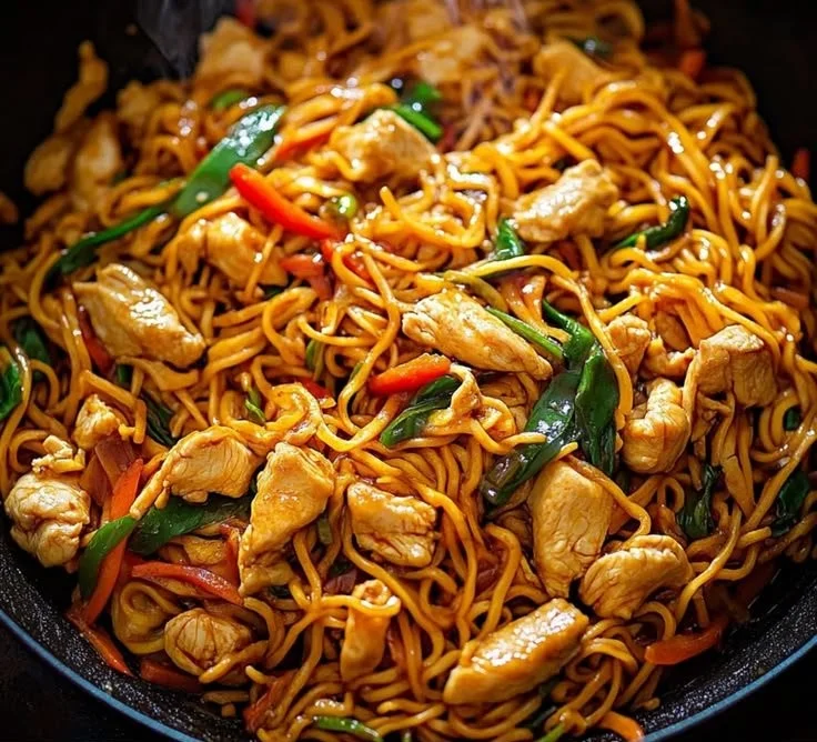 Delicious homemade chicken lo mein served in a bowl with colorful vegetables.
