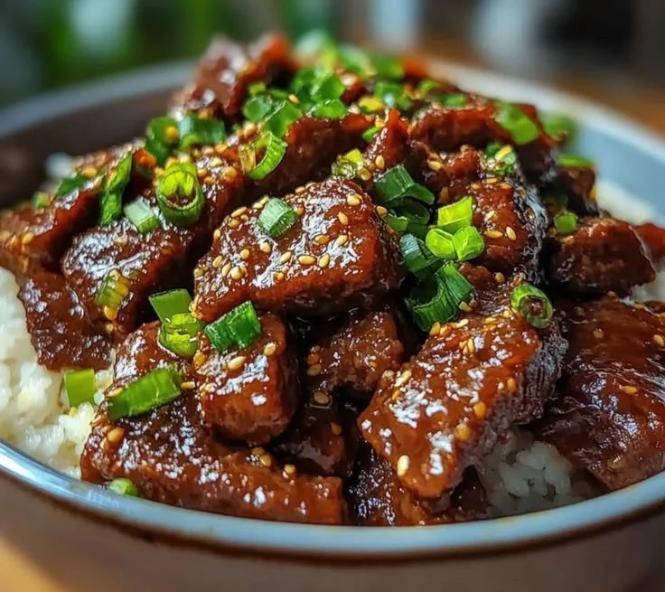 Delicious Crockpot Mongolian Beef served with rice and garnished with green onions.