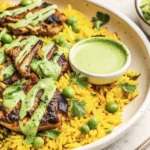 A plate of Peruvian chicken and rice adorned with fresh herbs and spices.