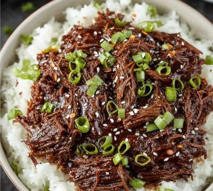 Slow Cooker Korean Beef 3 Slow Cooker Korean Beef garnished with green onions on a white plate.