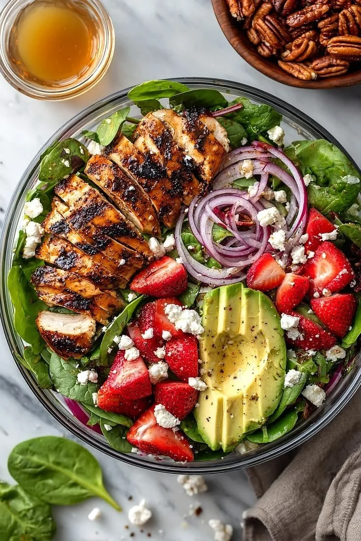 Strawberry spinach salad with chicken garnished with nuts and dressing