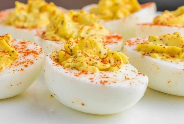 A plate of classic deviled eggs garnished with paprika and herbs